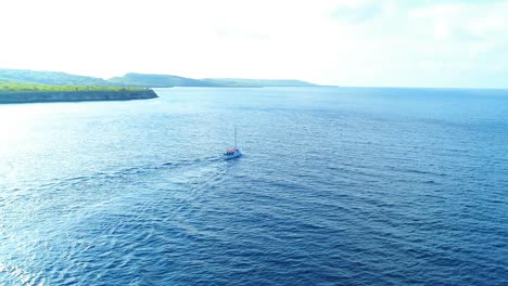 Aerial-orbit-drone-parallax-around-sailboat-and-large-wake-to-reveal-tropical-coastline