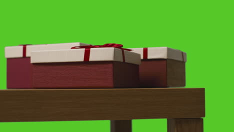 Close-Up-Of-Gift-Wrapped-Present-Boxes-On-Table-Shot-Against-Green-Screen-1