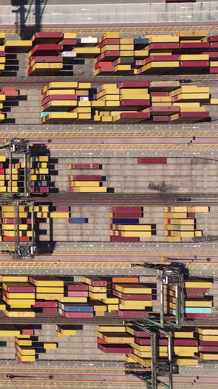 Vista aerea di un trafficato terminal container che mostra file di container marittimi e attività di movimentazione merci. La posizione facilita le spedizioni globali e il commercio internazionale