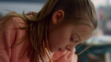 niña dibujando en un cuaderno en el escritorio en el aula. niño usando lápiz en la lección