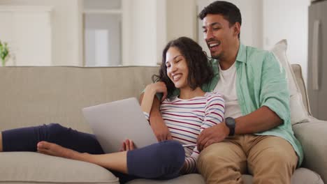 Pareja-Hispana-Sentada-En-El-Sofá-Mirando-La-Computadora-Portátil-Discutiendo