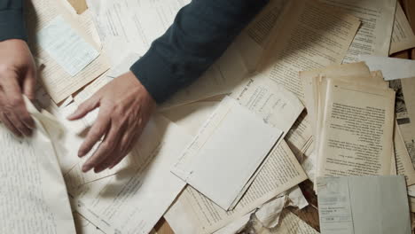 male hands nervously searching old documents. top shot