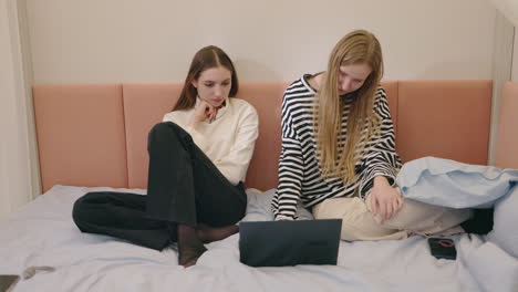 two young women studying on a bed