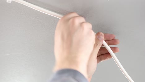 electrician prodessional nailing electric cable to roof with hammer