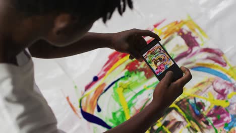 African-american-male-artist-taking-a-picture-of-his-painting-with-a-smartphone-at-art-studio