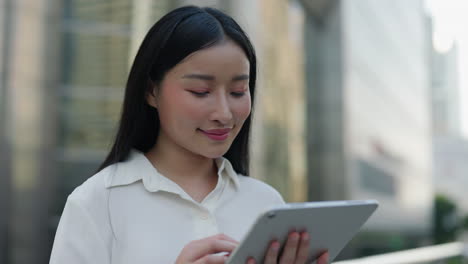 asian businesswoman using tablet outdoors