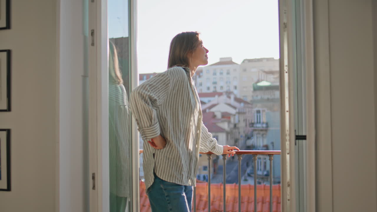 Travel woman leaning balcony admiring cityscape. Happy lady in evening sunlight