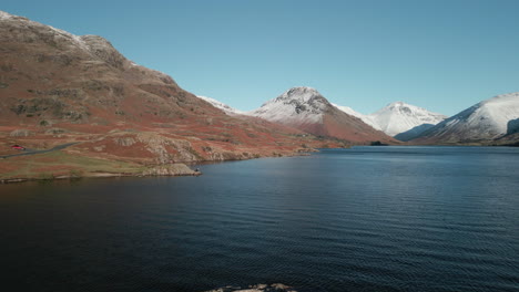 volando sobre una pequeña isla en un lago tranquilo hacia las montañas cubiertas de nieve en el distrito de los lagos wasdale uk