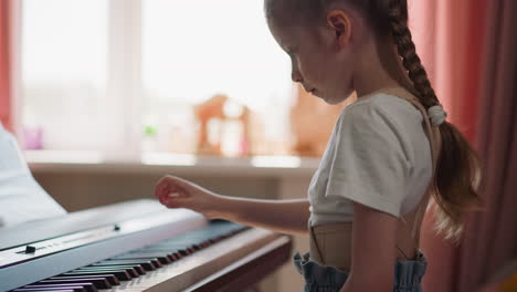 chica diligente toca el piano electrónico con la mano derecha