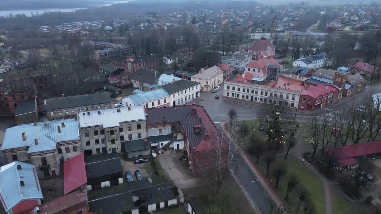 Aerial perspective of Limbazi city showcasing colorful rooftops, historical buildings, a church, and surrounding greenery. A serene, small-town charm is evident in this view.
