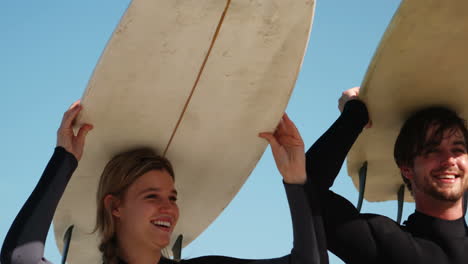 couple holding surfboard over head