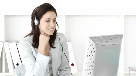 Laughing-businesswoman-working-at-a-computer-with-headset-on