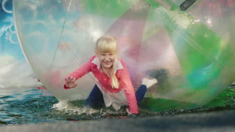 the child plays inside a transparent ball on the water recreation in amusement park happy holidays 4