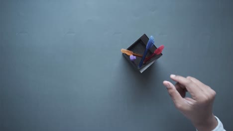 pens in a small box on a gray surface