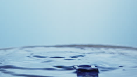 ice cube splashes in clean water creating a dark purple fountain