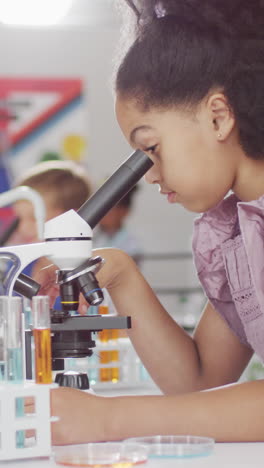 video of happy biracial girl with microscope during lesson