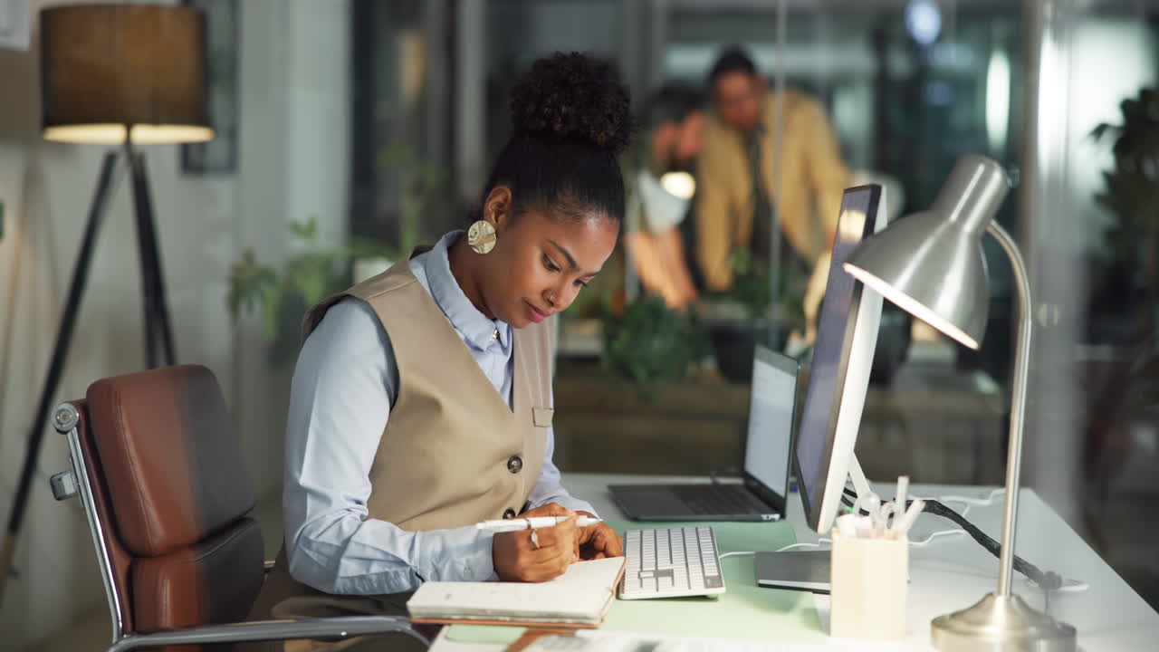 Focused Woman Writing in Notebook at Desk in Modern Office at Night