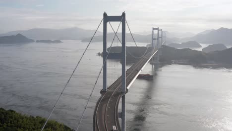 el barco viaja bajo el puente kurushima kaikyo, shimanami kaido, japón