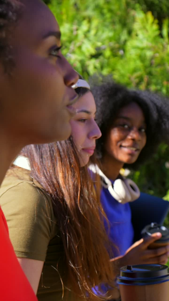 Tre giovani donne eterogenee che parlano e sorridono all'aperto
