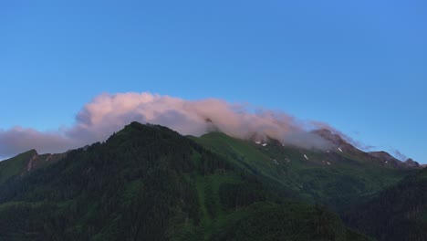 Deep-blue-sky-above-mountain-range-covered-in-rock,-snow,-trees-and-foliage