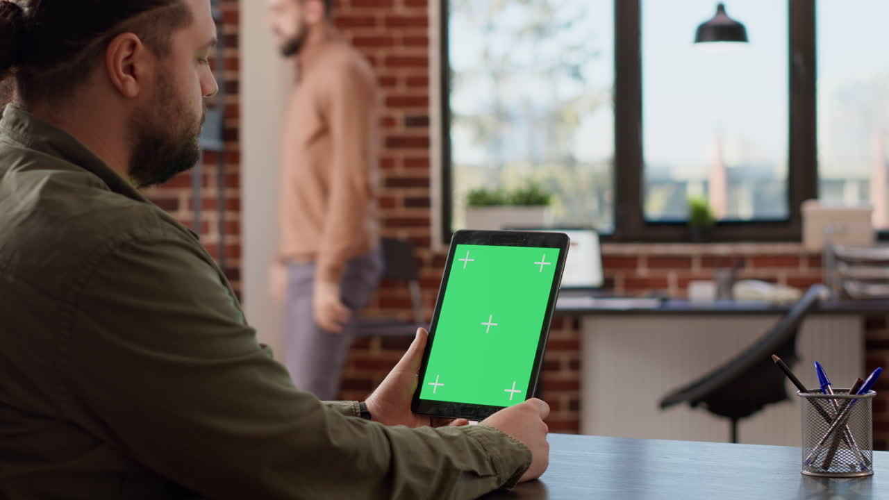 Male freelancer holding digital tablet with greenscreen display