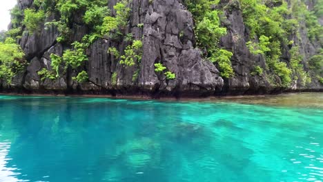 isla tropical negra y rocosa con acantilados empinados en aguas oceánicas turquesas cristalinas en palawan, filipinas