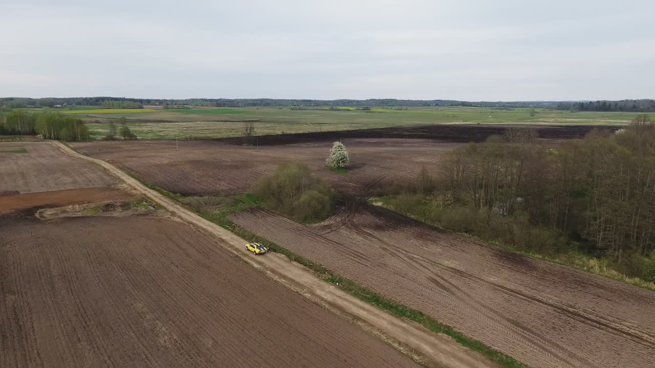 Yellow With Black Stripes Classic Ford Consul Rides On A Gravel Road. 4K Aerial Footage