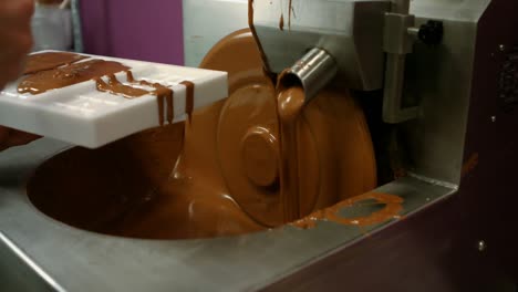 worker filling mould with melted chocolate