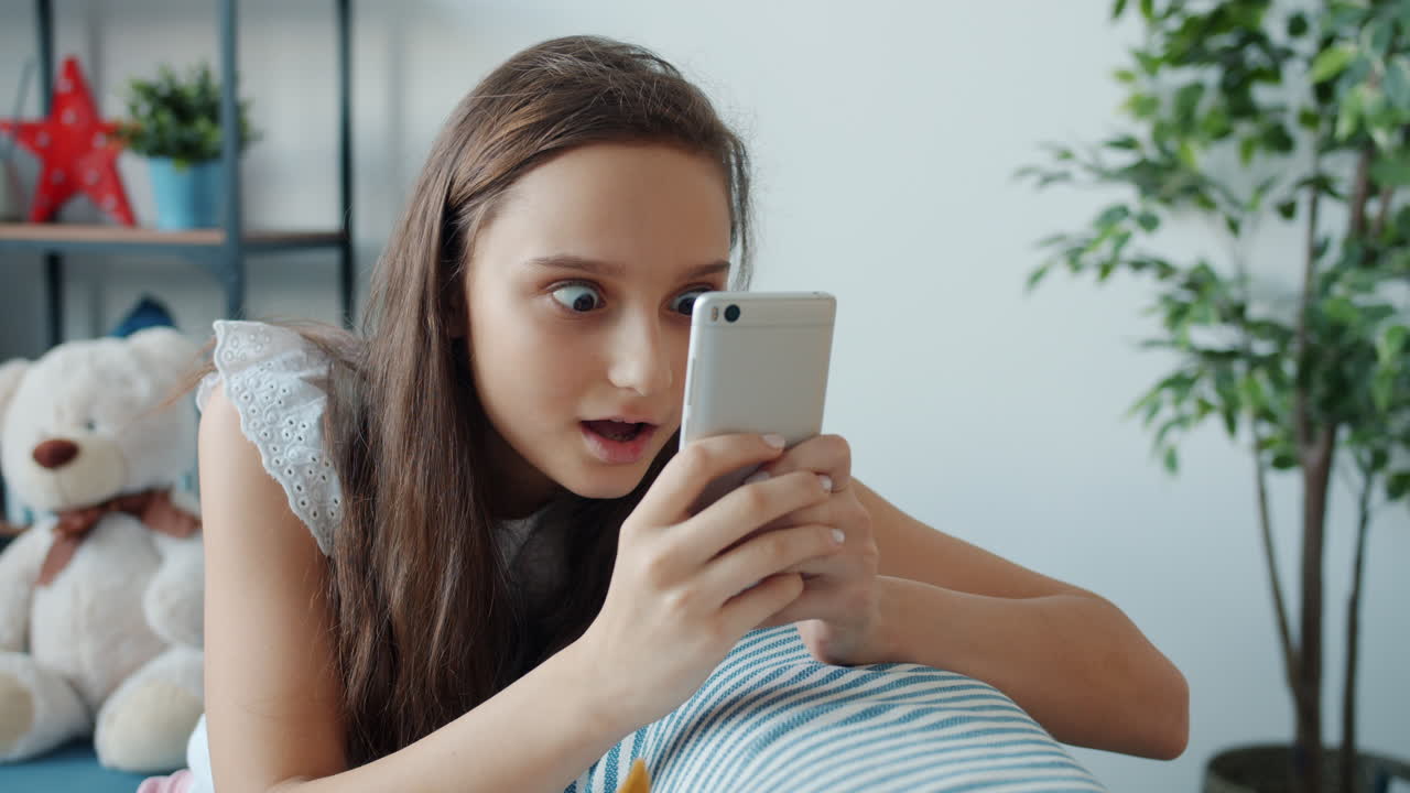 Teenage girl looking at phone with surprised expression