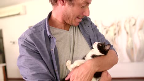 modern dad holding cat on his arms and smiles