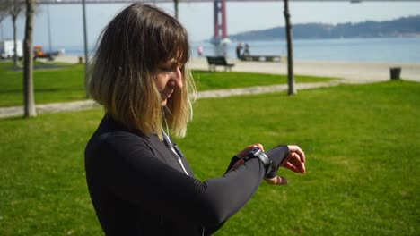 chica atlética con auriculares usando un reloj inteligente al aire libre