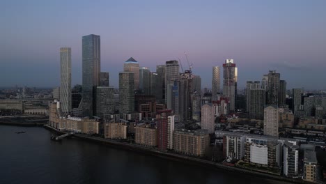 Vista-Aérea-De-La-Hora-Azul-Del-Horizonte-De-Canary-Wharf-Sobre-El-Río-Támesis,-Londres