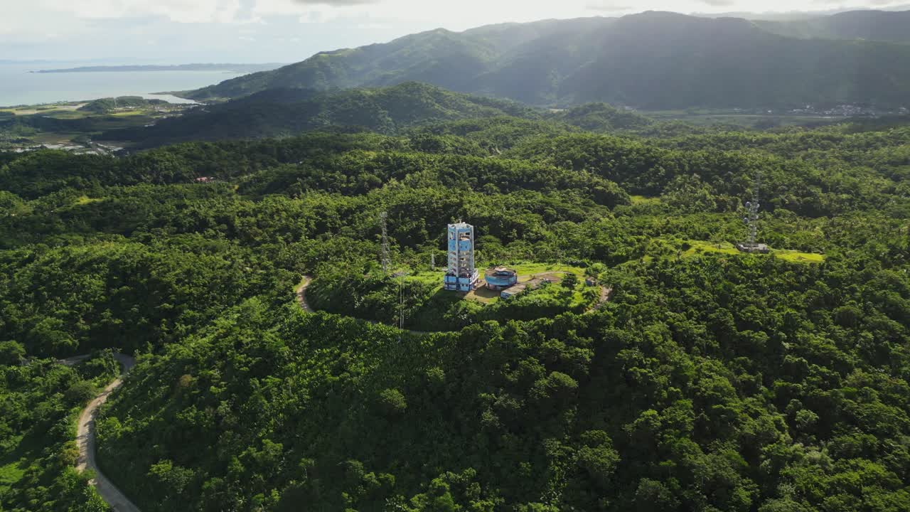 Aerial orbit of PAGASA weather Doppler Radar Station atop lush tropical island hills during daytime at Buenavista, Catanduanes, Philippines