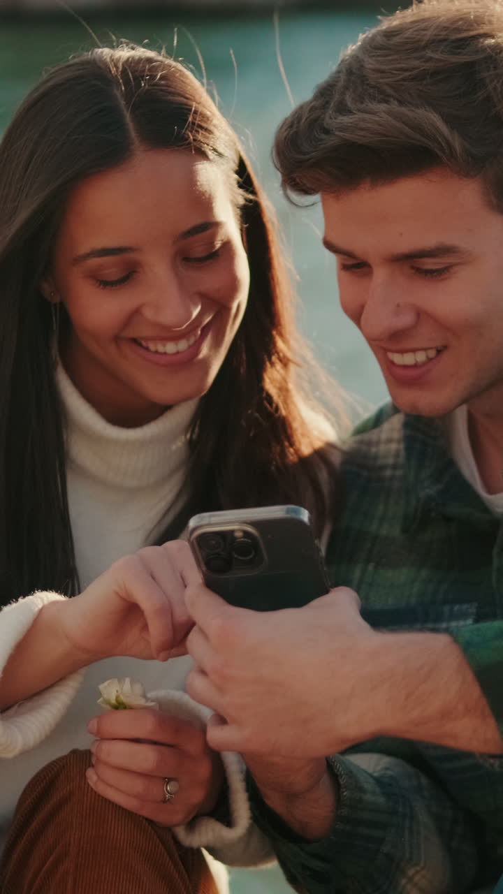 Happy Couple By The River Looking At Phone