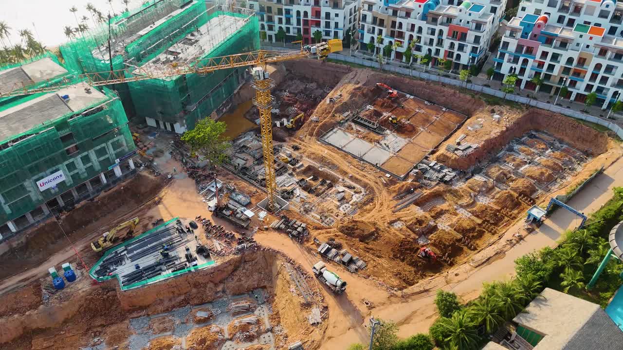 Aerial view of the construction site for the VinHomes resort on Phu Quoc Island, Vietnam. The site shows ongoing work on buildings modeled after Santorini architecture, with cranes and machinery.