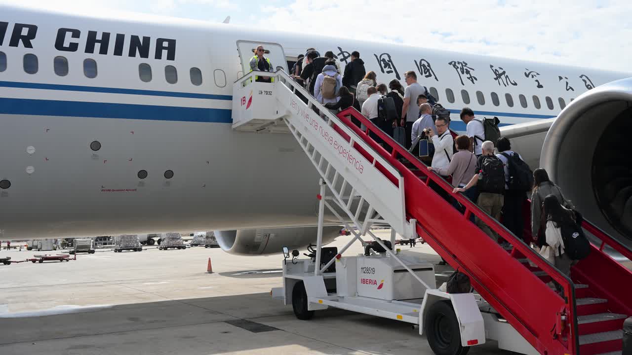 Passengers climb the boarding stairs, also called a boarding ramp, to board an Air China plane on the runway at Beijing International Airport, China.