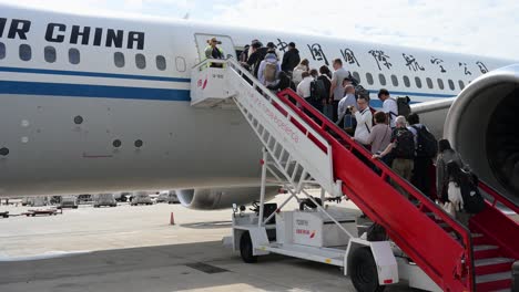 passengers climb the boarding stairs, also called a boarding ramp, to board an air china plane on the runway at beijing international airport, china.