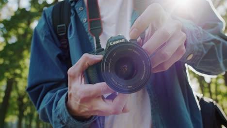 close-up shot of a person holding a canon camera, capturing video outdoors
