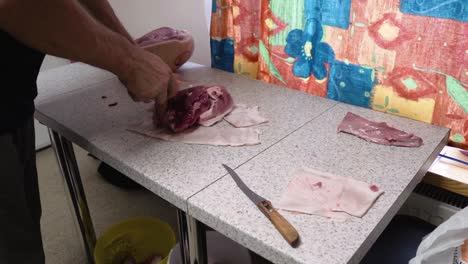 carnicero cortando carne de cerdo cruda con un cuchillo en una cocina, sepárela de la piel