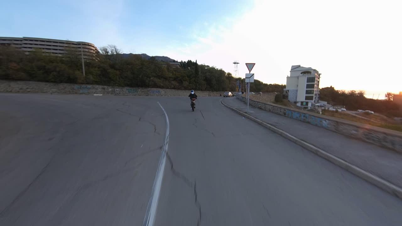 emocionante toma de acción de un acrobático haciendo un caballito en una motocicleta en las calles al atardecer