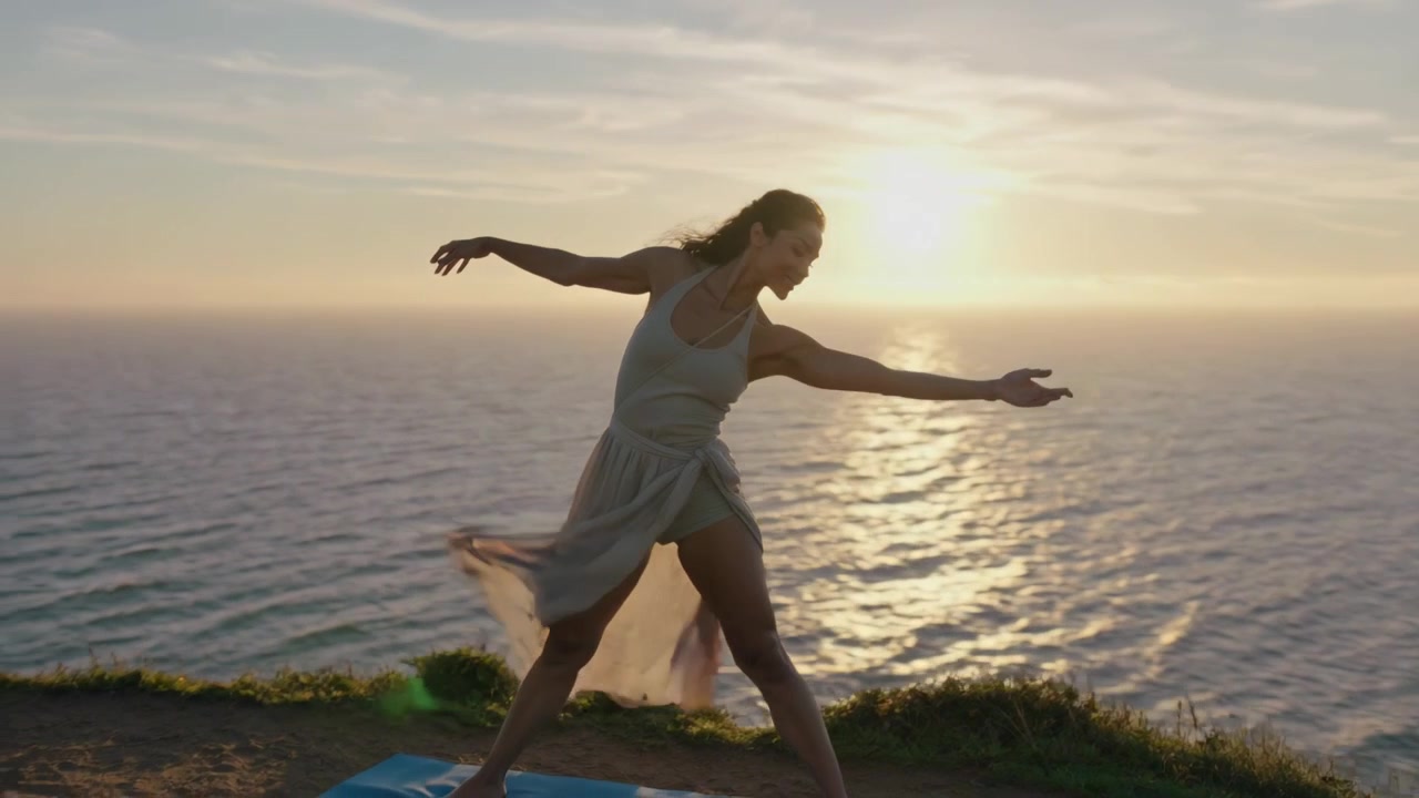 Donna che volteggia facendo passi di danza su una scogliera costiera, il tramonto invita a movimenti sereni con una gonna fluida.