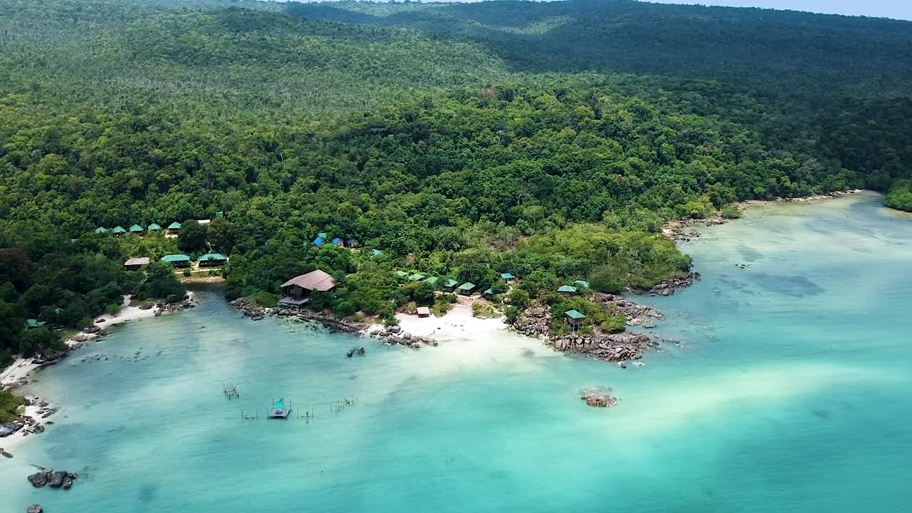 Aerial of white sand beach with straw huts along Forrest coastline with turquoise blue sea