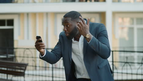 Angry-african-businessman-video-chatting-outside.-Business-man-calling-phone