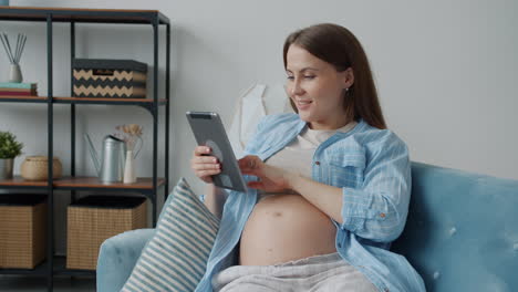 pregnant woman using a tablet at home