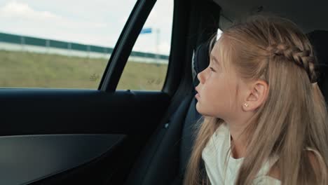 Niña-Caucásica-De-8-Años-Mirando-Por-La-Ventana-Del-Auto-Mientras-Viaja-En-Auto.