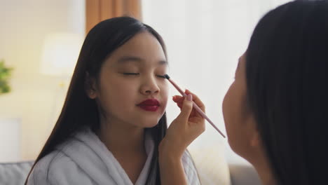 mother applying makeup to daughter