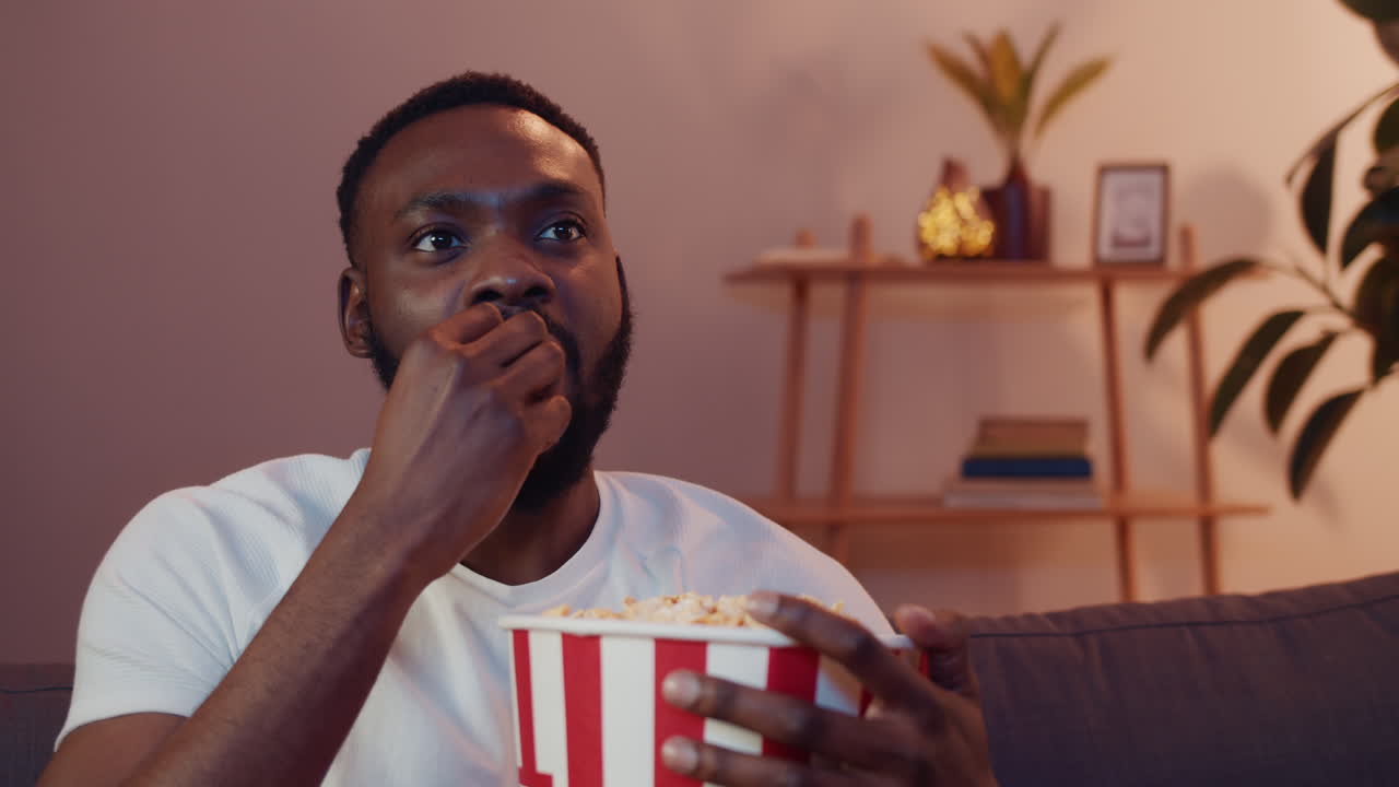 hombre viendo la tv con palomitas de maíz