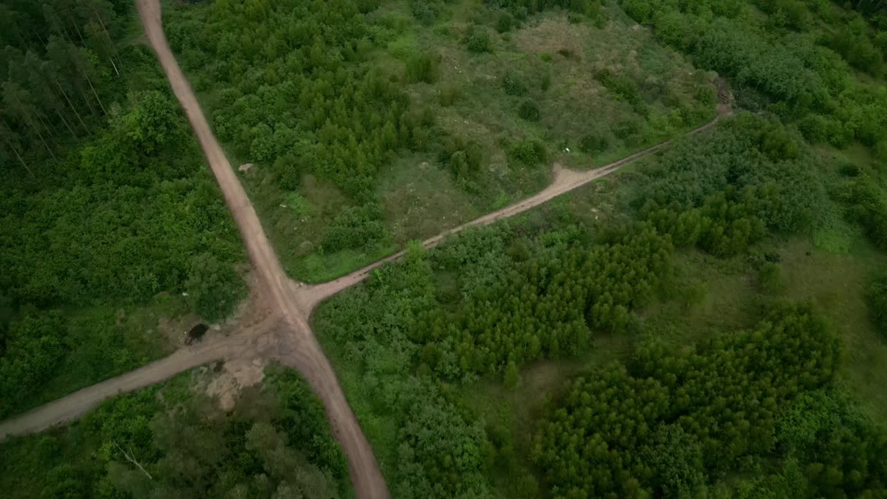 Drone view of a crossroads of dirt roads in the middle of a dark forest