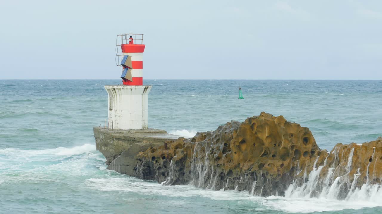Lighthouse on Rocky Coast with Waves Crashing