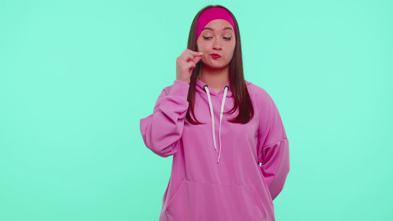 소녀는 입술에 지표손가락을 누르며 침을 지시합니다. 신호는 비밀을 말하지 않습니다. 조용히하십시오.